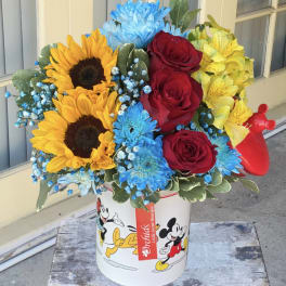 Bouquet of sunflowers, red roses, blue chrysanthemums, and yellow alstroemeria in a Mickey Mouse tin