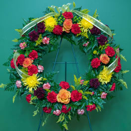 Circular floral wreath with red, yellow, and orange flowers on a stand