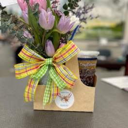 Gift caddy with pastel tulip bouquet, plaid bow, and iced tea cup on a table