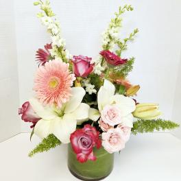 Mixed bouquet in a green glass vase with pink, white, and burgundy flowers