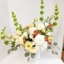 White and pale yellow floral arrangement in a ribbed white vase
