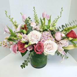 Mixed pink and white flowers arranged in a green glass vase