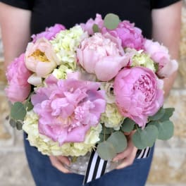 Pink peonies and pale hydrangeas in a clear vase with eucalyptus