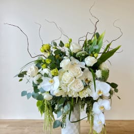 White roses and orchids in a tall white vase