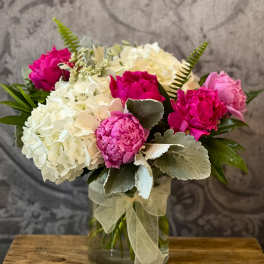 Pink and white floral bouquet in a glass vase with a sheer ribbon