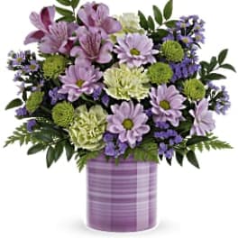 Lavender daisies, green mums, and pale carnations in a striped lavender ceramic cylinder vase