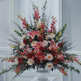 Large mixed floral arrangement in a white pedestal vase
