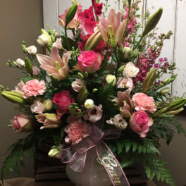Pink and white floral arrangement in a white vase with a ribbon bow