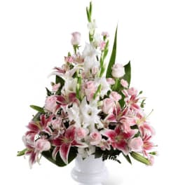 Pink and white floral arrangement in a white pedestal vase