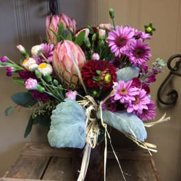 Mixed bouquet with pink protea and purple daisies in a vase