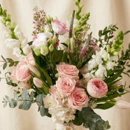 Tall hand-tied bouquet of pale pink roses, tulips, and white flowers tied with a ribbon
