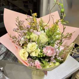 Pastel bouquet of pink, yellow, and white flowers wrapped in paper