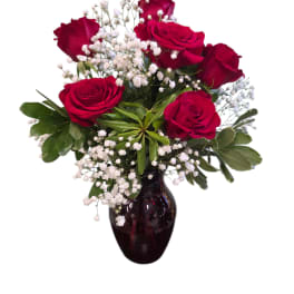 Red rose bouquet in a vase beside a lavender teddy bear