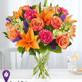 Bouquet of orange lilies, roses, and pink carnations in a glass vase