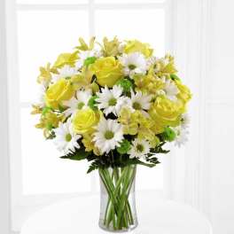 Yellow roses and white daisies in a clear glass vase