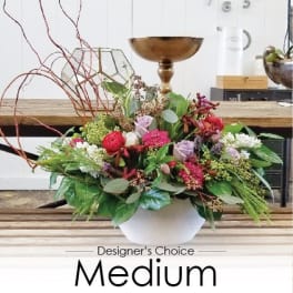 Mixed floral arrangement in a white bowl vase with red, pink, and lavender blooms