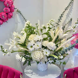 White floral arrangement in a white basket with pink wall accents