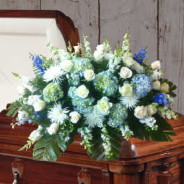 White and blue floral spray on a casket