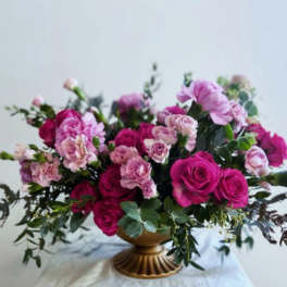 Pink and purple roses with carnations in a low vase