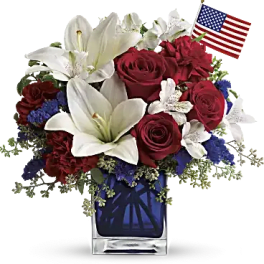 Red roses and white lilies in a glass vase with a small American flag