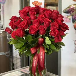 Bouquet of red roses in a glass vase with a red ribbon