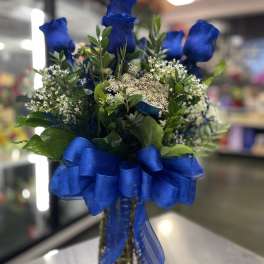 Blue roses in a glass vase with a large blue ribbon