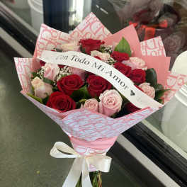 Bouquet of red and pink roses with a ribbon reading "Con Todo Mi Amor"