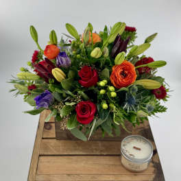 Colorful mixed bouquet in a wooden box with a small candle