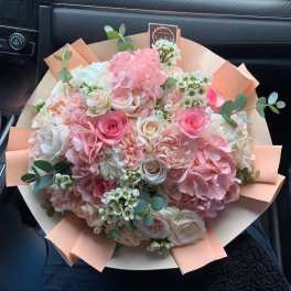 Bouquet of pink and white roses with hydrangeas and eucalyptus in peach wrap