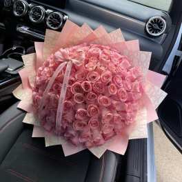 Large bouquet of pink roses wrapped in pink paper with a ribbon