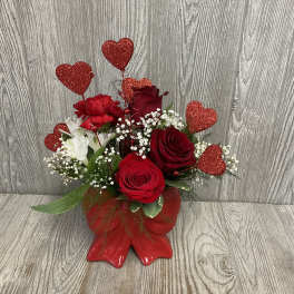 Red roses and white flowers in a red vase with glitter heart picks