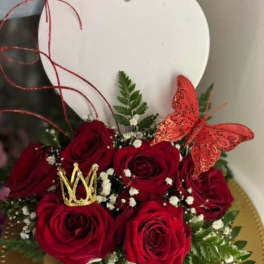 Red roses arranged with a gold crown and red butterfly in a heart-shaped box