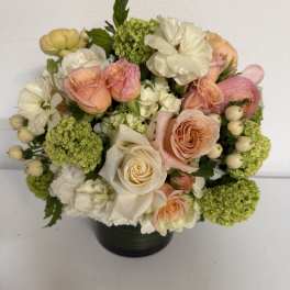 Bouquet of peach and white roses with green hydrangeas in a black vase
