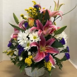 Pink lilies and white daisies in a low basket arrangement