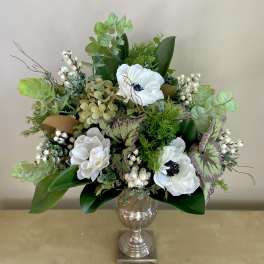 White flowers arranged in a silver vase with mixed greenery
