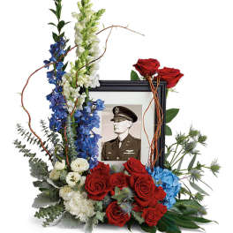 Framed memorial photo surrounded by red, white, and blue flowers