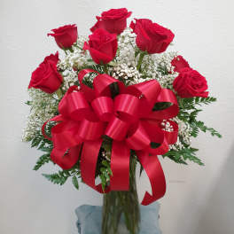 Bouquet of red roses with baby's breath in a glass vase and red ribbon