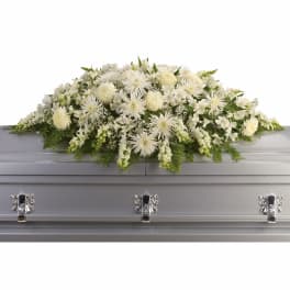 White floral casket spray with mixed blooms on a silver casket