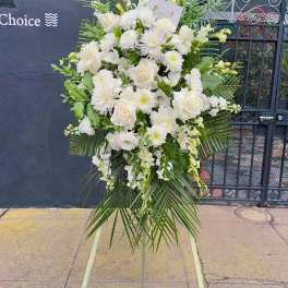Tall white floral standing spray on an easel with palm fronds