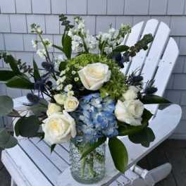 White roses and blue hydrangea in a glass vase