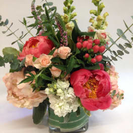 Mixed bouquet in a square glass vase with pink peonies and peach roses