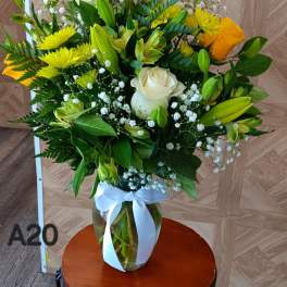 Bouquet of yellow and white roses with lilies in a glass vase