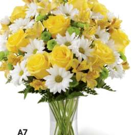 Yellow roses and white daisies arranged in a clear glass vase