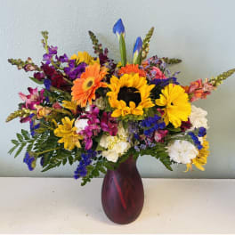 Colorful mixed bouquet with sunflowers, gerbera daisies, and alstroemeria in a red vase