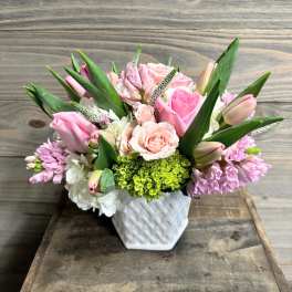 Pink and white floral arrangement in a white woven vase