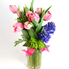 Pink tulips and purple hyacinths in a clear glass vase