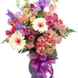 Mixed bouquet of pink, purple, and white flowers in a vase with a purple ribbon