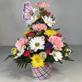 Colorful mixed flower arrangement in a plaid container with a butterfly pick