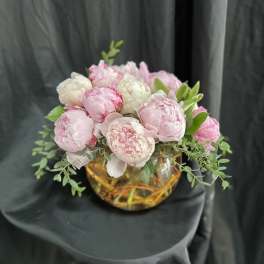 Pink and white peonies arranged in a low glass bowl