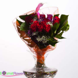 Bouquet of red roses in a clear glass vase with orange wrap